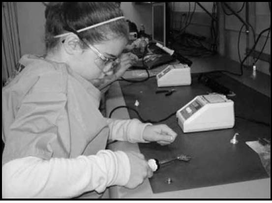 A camper soldering wires to her printed circuit board (PCB) in the Flower Power workshop.