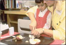 Image of children learning to cut apples.